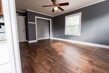 An empty living room with wood floors and a ceiling fan